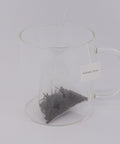 Preparación de té Dian Hong en bolsita piramidal, mostrando una infusión de color ámbar intenso durante el proceso de preparación.